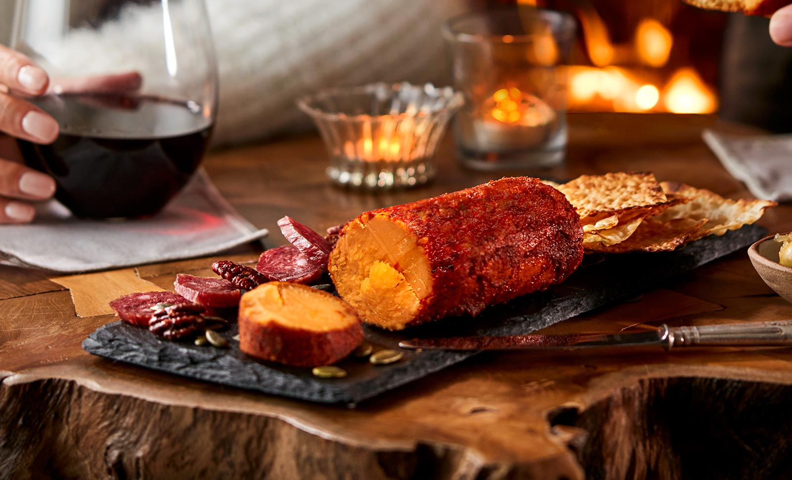 A Chipotle seasoned cheddar cheese log served with sliced salami, walnuts and crackers.