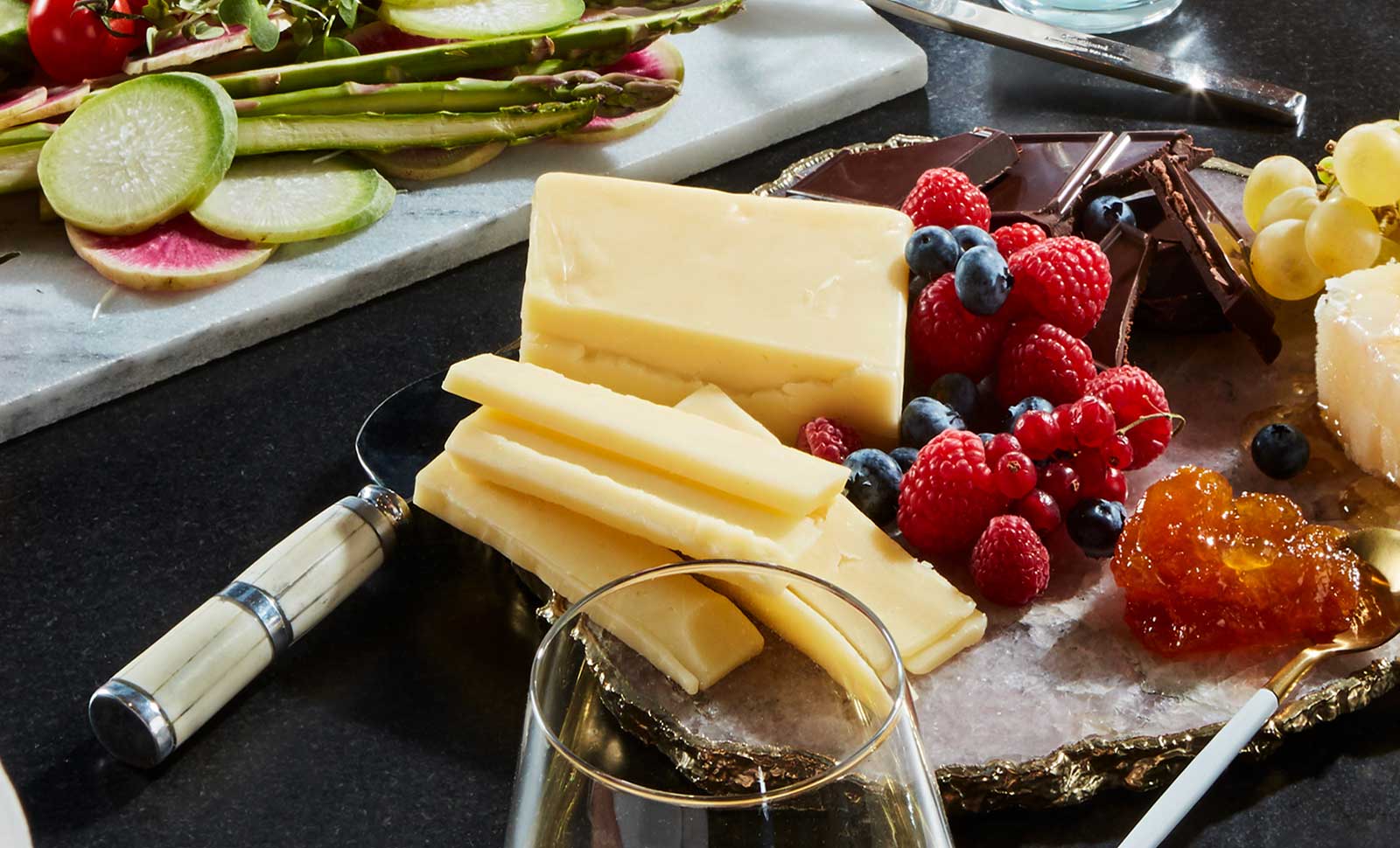 Slices of one-year aged cheddar next to raspberries and blueberries.