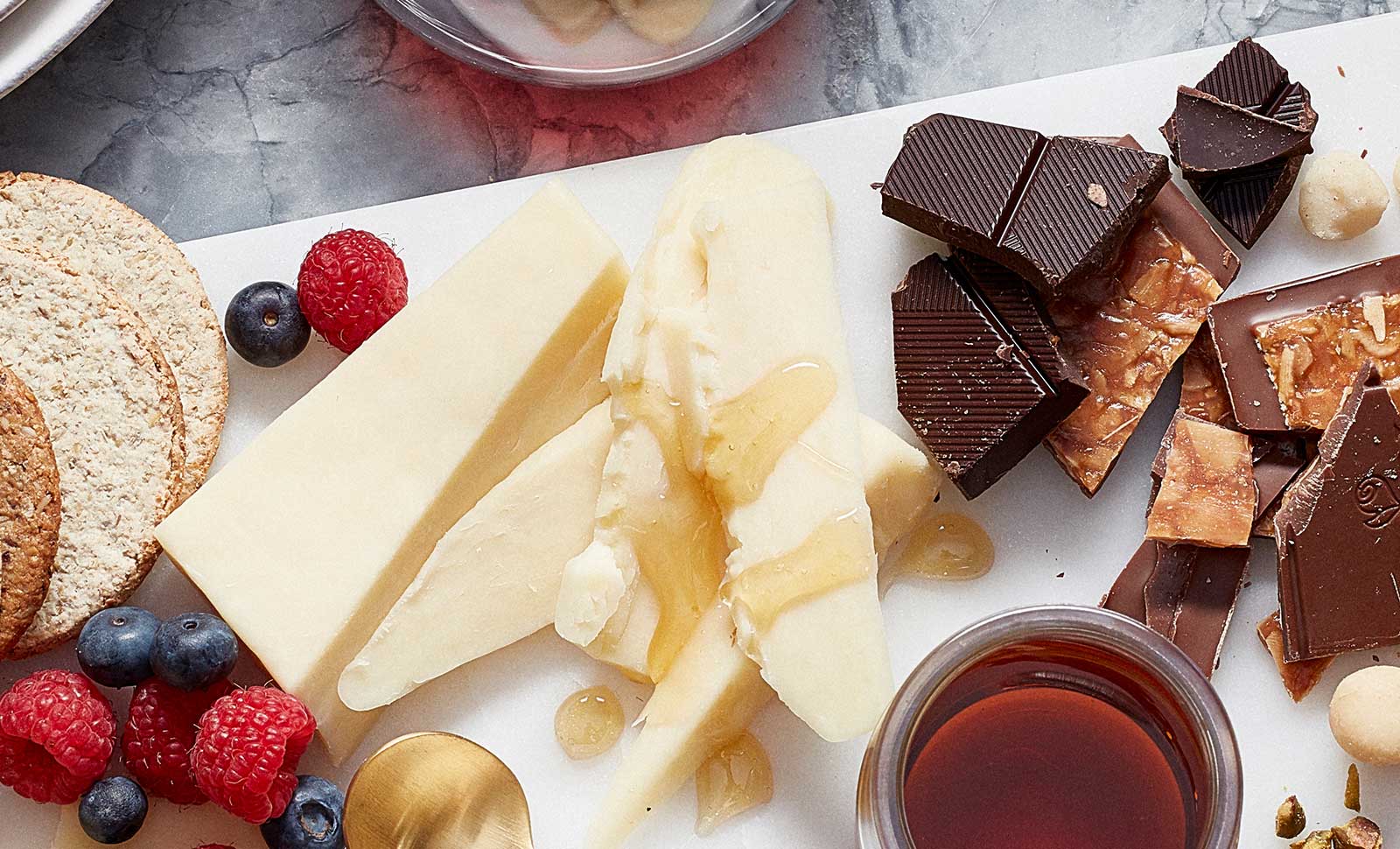 Pieces of artisan maple cheddar cheese served with fruit and pieces of dark chocolate.