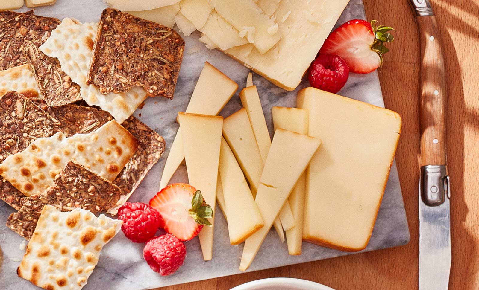 Eight pieces of naturally smoked gouda cheese served on a plate with multigrain crackers.