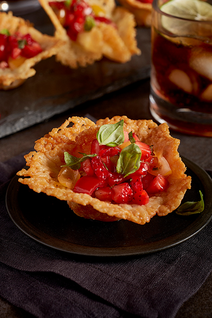 An up-close shot of cheddar cheese cups with peppery strawberry salsa in front of plated food.