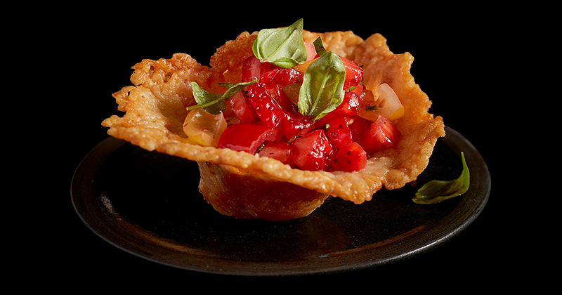 An up-close shot of cheddar cheese cups with peppery strawberry salsa.